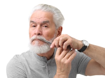 Senior man trimming beard with scissors on white background