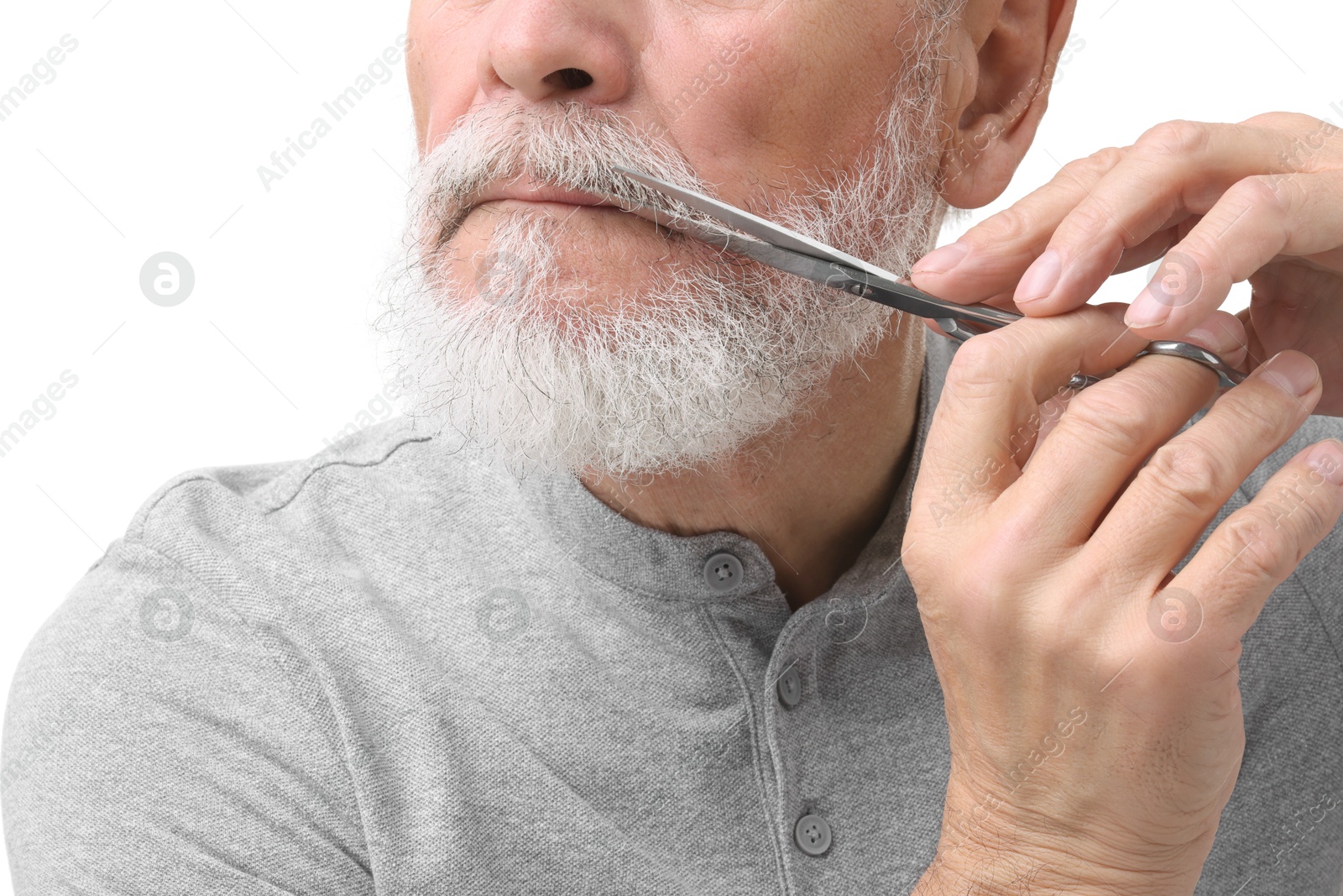 Photo of Senior man trimming beard with scissors on white background, closeup