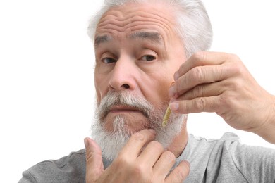 Photo of Senior man applying oil onto his beard on white background