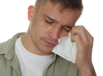 Photo of Crying man wiping tears with tissue on white background