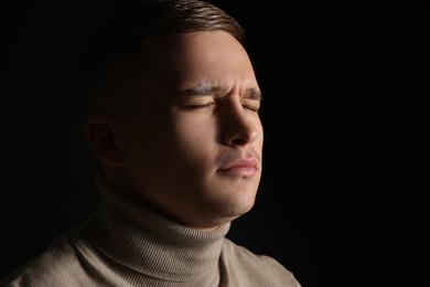 Photo of Distressed young man crying on black background