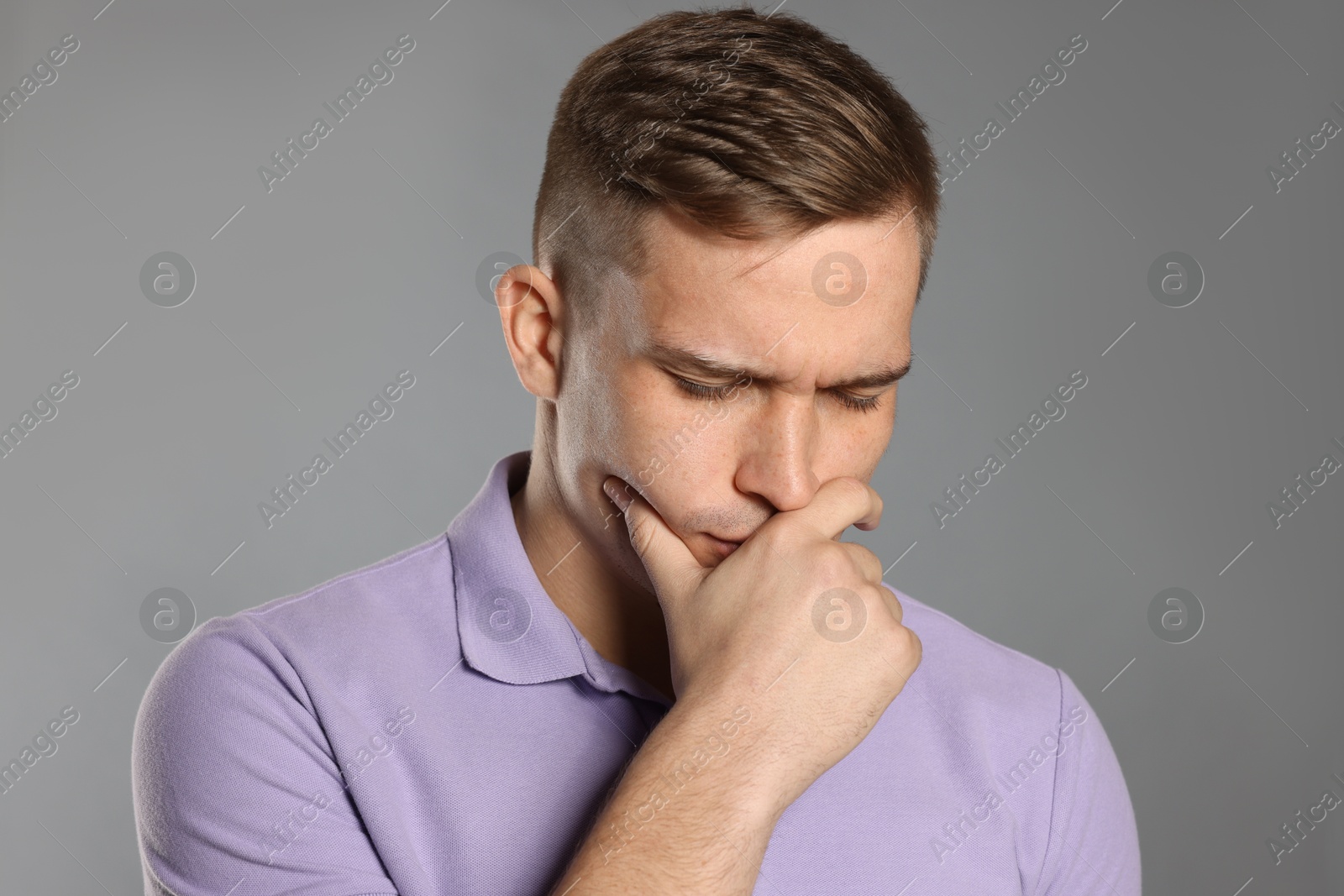 Photo of Distressed young man crying on grey background