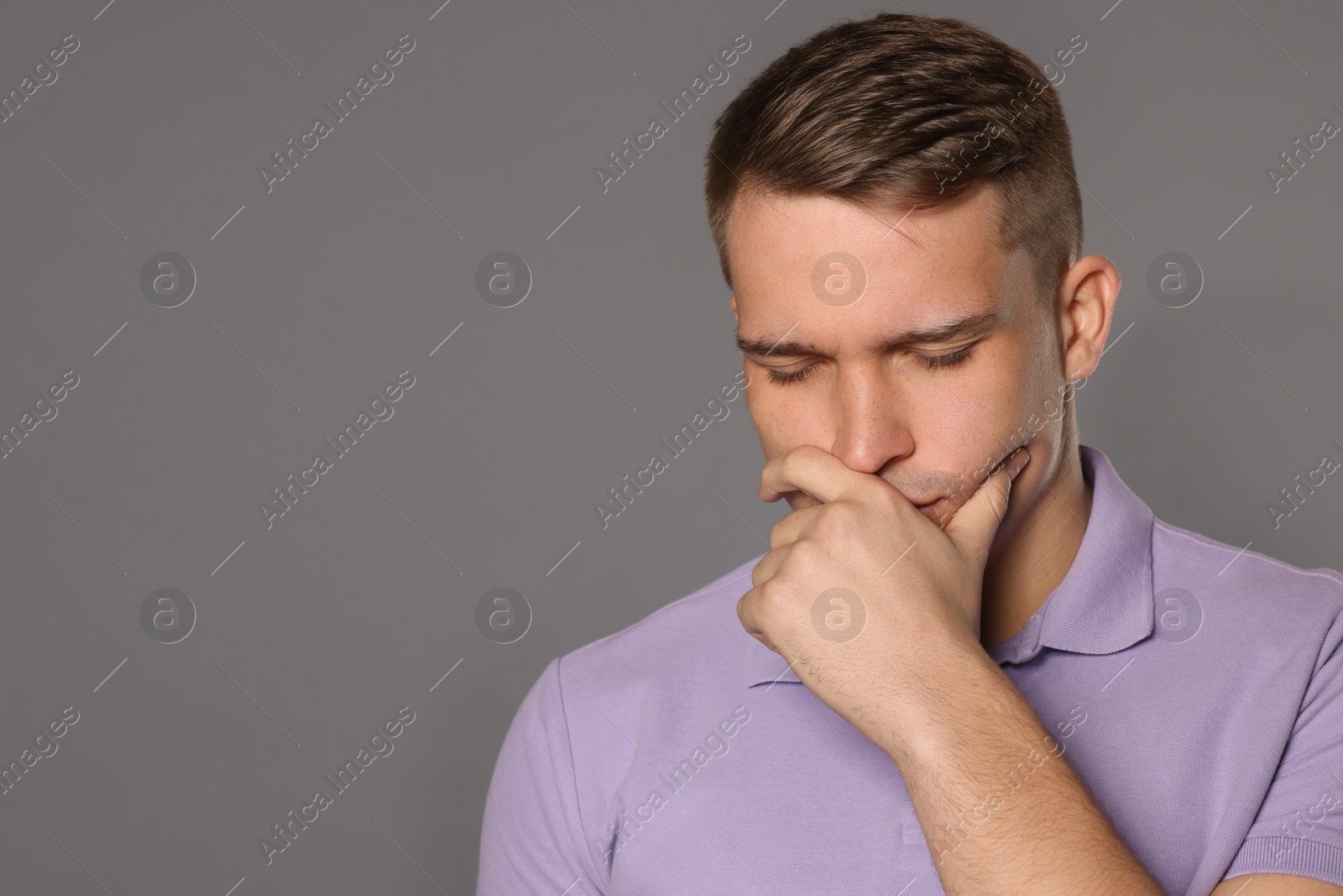 Photo of Distressed young man crying on grey background. Space for text