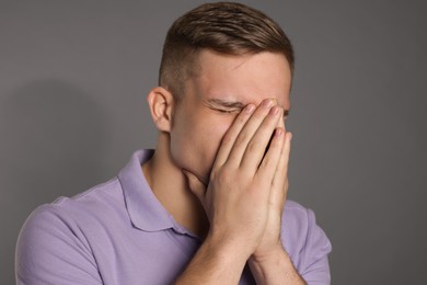 Photo of Distressed young man crying on grey background