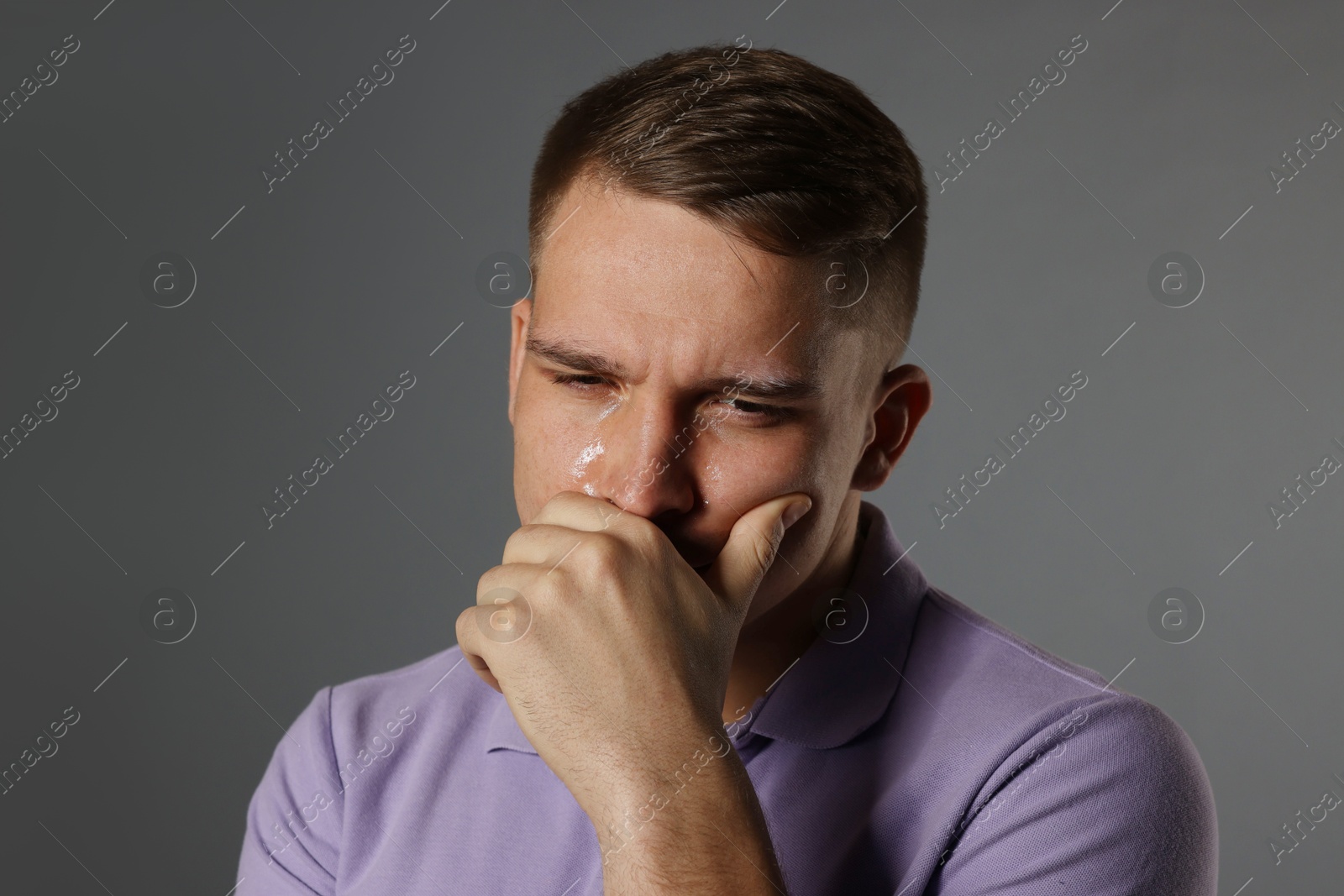 Photo of Distressed young man crying on grey background