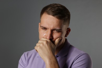 Photo of Distressed young man crying on grey background