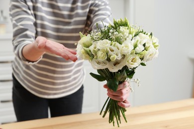 Photo of Florist with beautiful wedding bouquet indoors, closeup