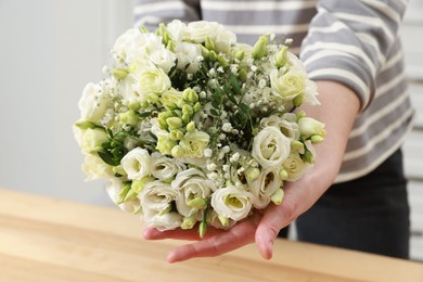 Photo of Florist with beautiful wedding bouquet indoors, closeup