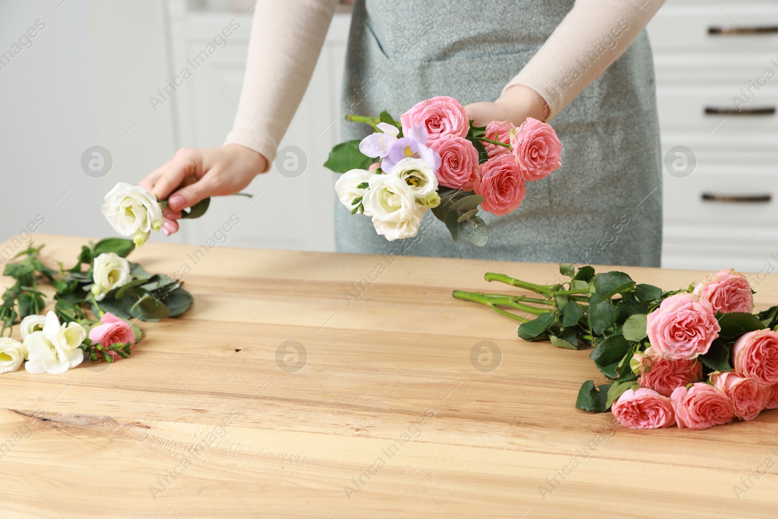 Photo of Florist making beautiful wedding bouquet at wooden table indoors, closeup