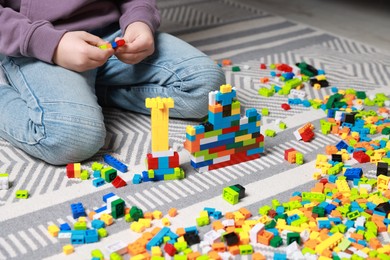 Photo of Cute boy playing with building blocks on floor at home, closeup