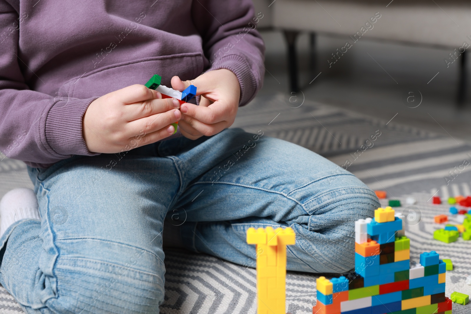 Photo of Cute boy playing with building blocks on floor at home, closeup