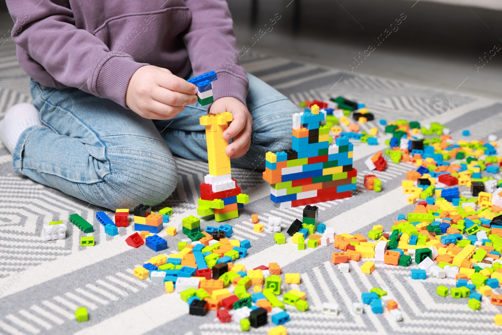 Photo of Cute boy playing with building blocks on floor at home, closeup