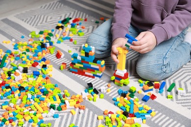 Photo of Cute boy playing with building blocks on floor at home, closeup