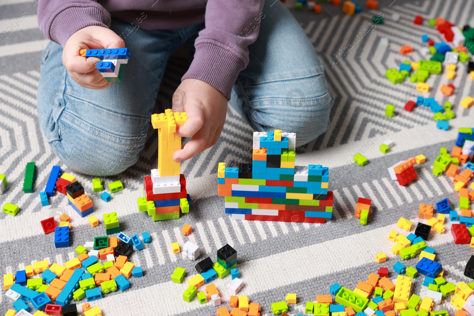 Photo of Cute boy playing with building blocks on floor at home, closeup