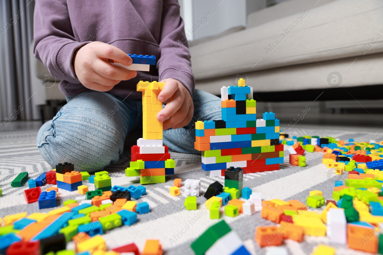 Photo of Cute boy playing with building blocks on floor at home, closeup