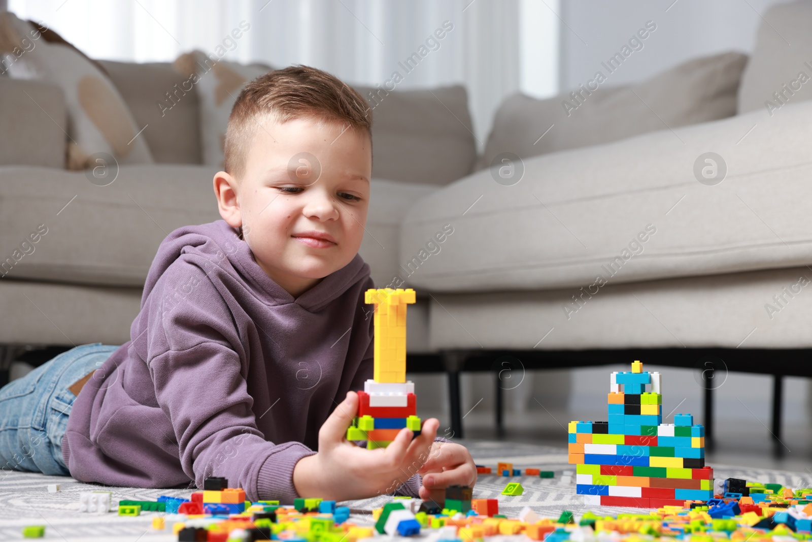 Photo of Cute boy playing with building blocks on floor at home. Space for text