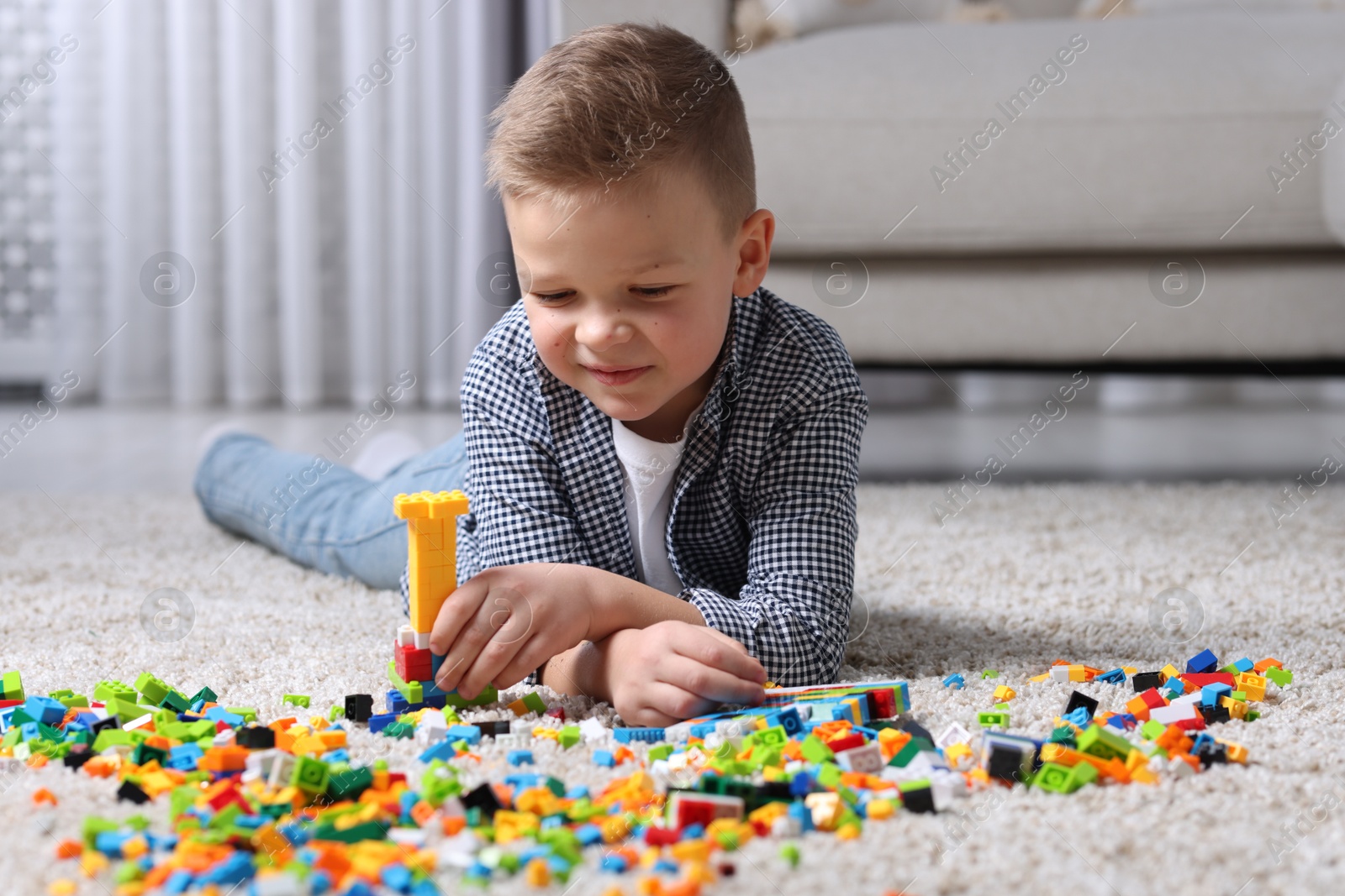 Photo of Cute boy playing with building blocks on floor at home