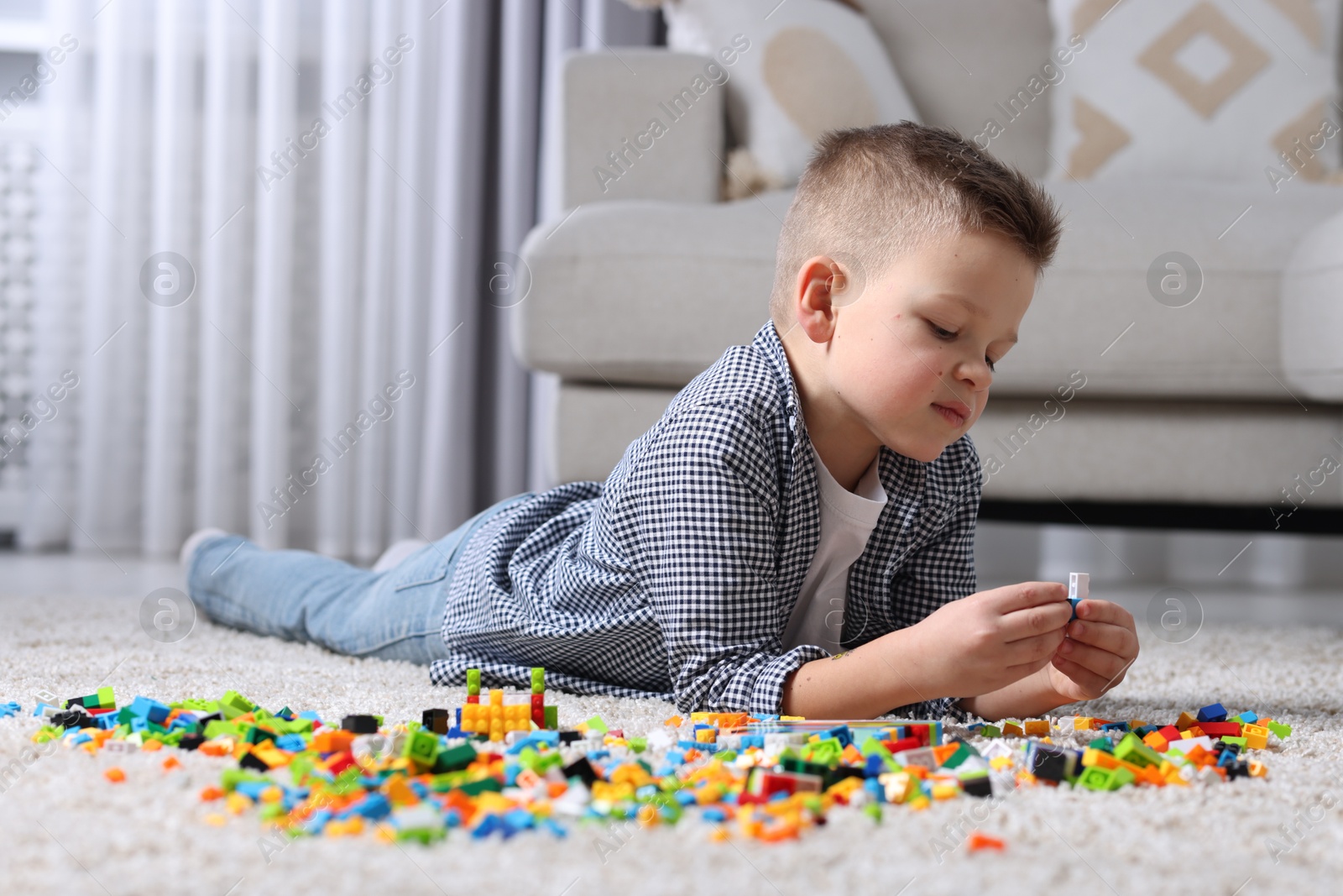 Photo of Cute boy playing with building blocks on floor at home