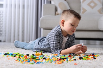 Photo of Cute boy playing with building blocks on floor at home