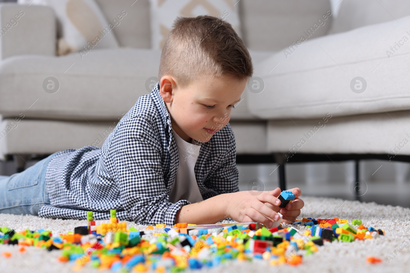 Photo of Cute boy playing with building blocks on floor at home