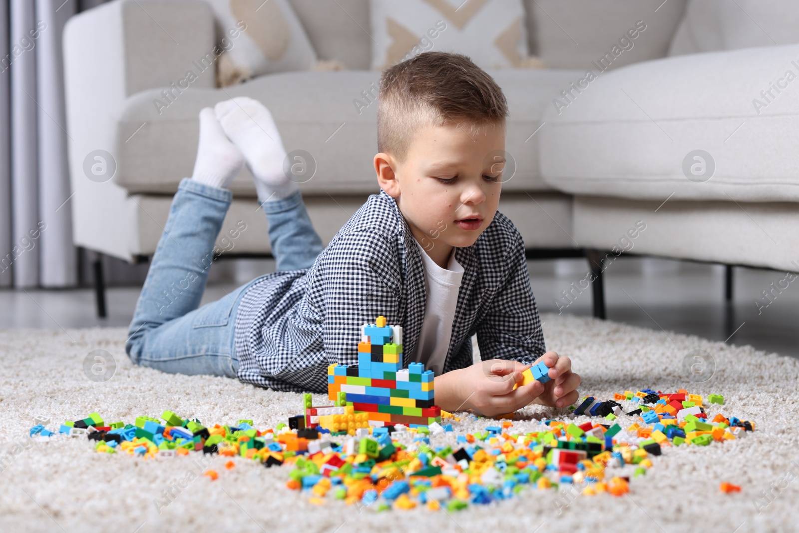 Photo of Cute boy playing with building blocks on floor at home