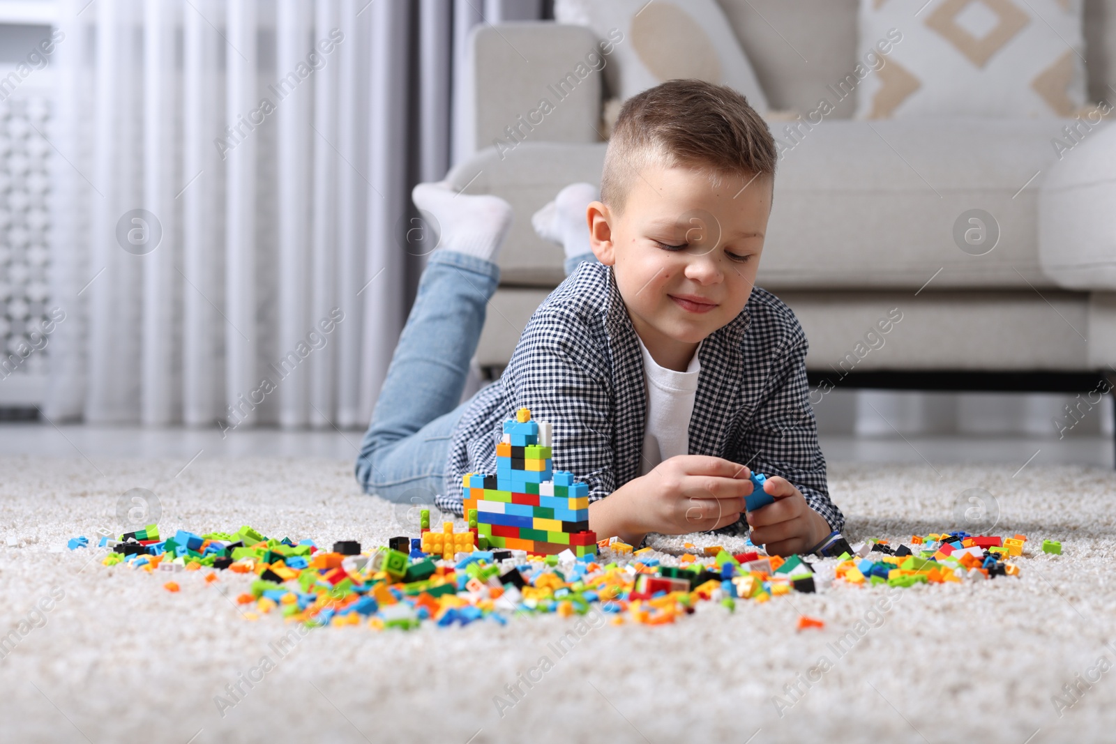 Photo of Cute boy playing with building blocks on floor at home