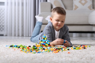 Photo of Cute boy playing with building blocks on floor at home