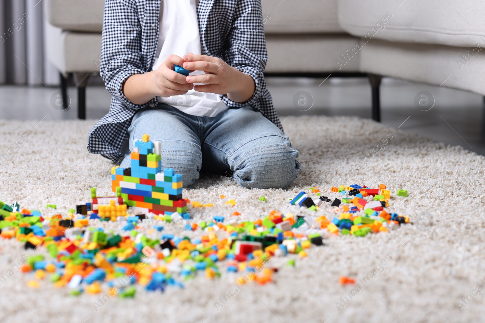 Photo of Cute boy playing with building blocks on floor at home, closeup