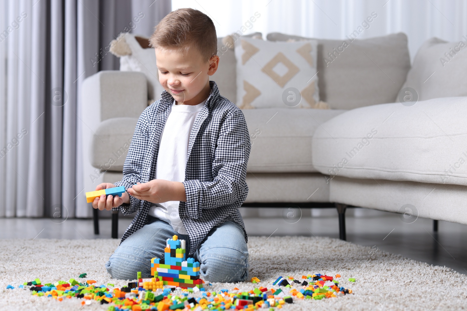 Photo of Cute boy playing with building blocks on floor at home. Space for text