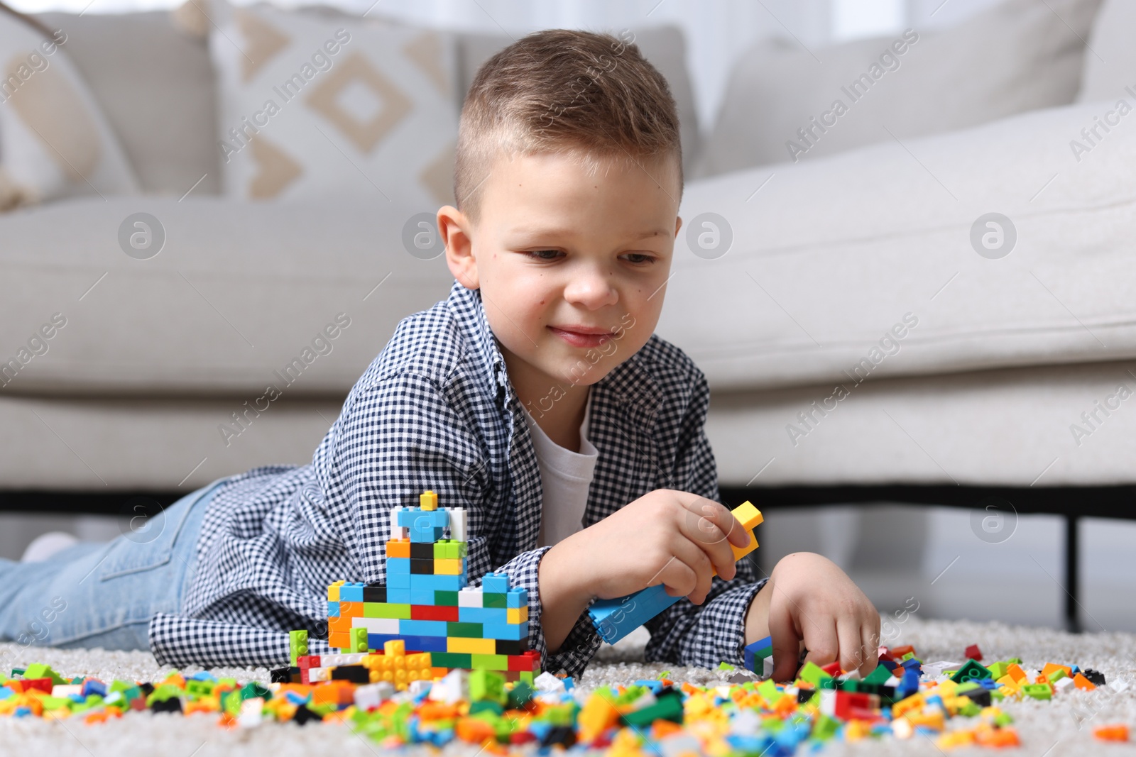 Photo of Cute boy playing with building blocks on floor at home