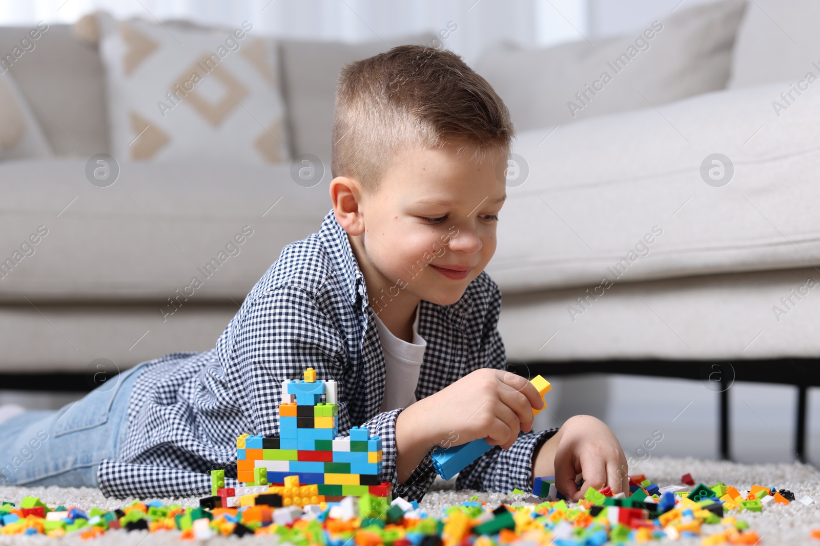 Photo of Cute boy playing with building blocks on floor at home