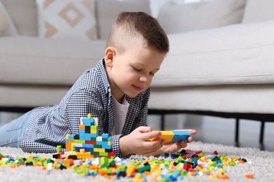 Photo of Cute boy playing with building blocks on floor at home