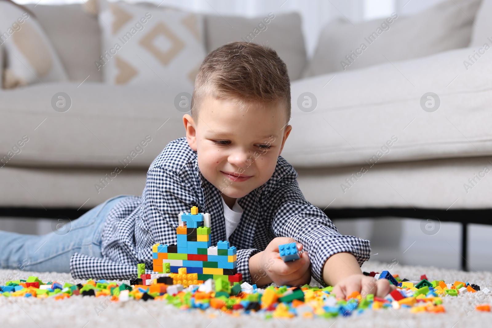 Photo of Cute boy playing with building blocks on floor at home