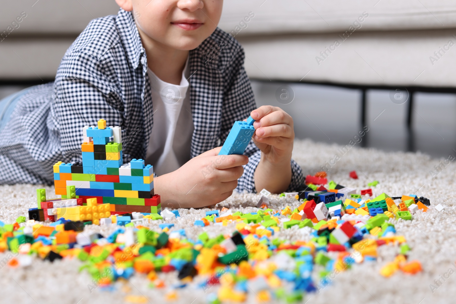 Photo of Cute boy playing with building blocks on floor at home, closeup