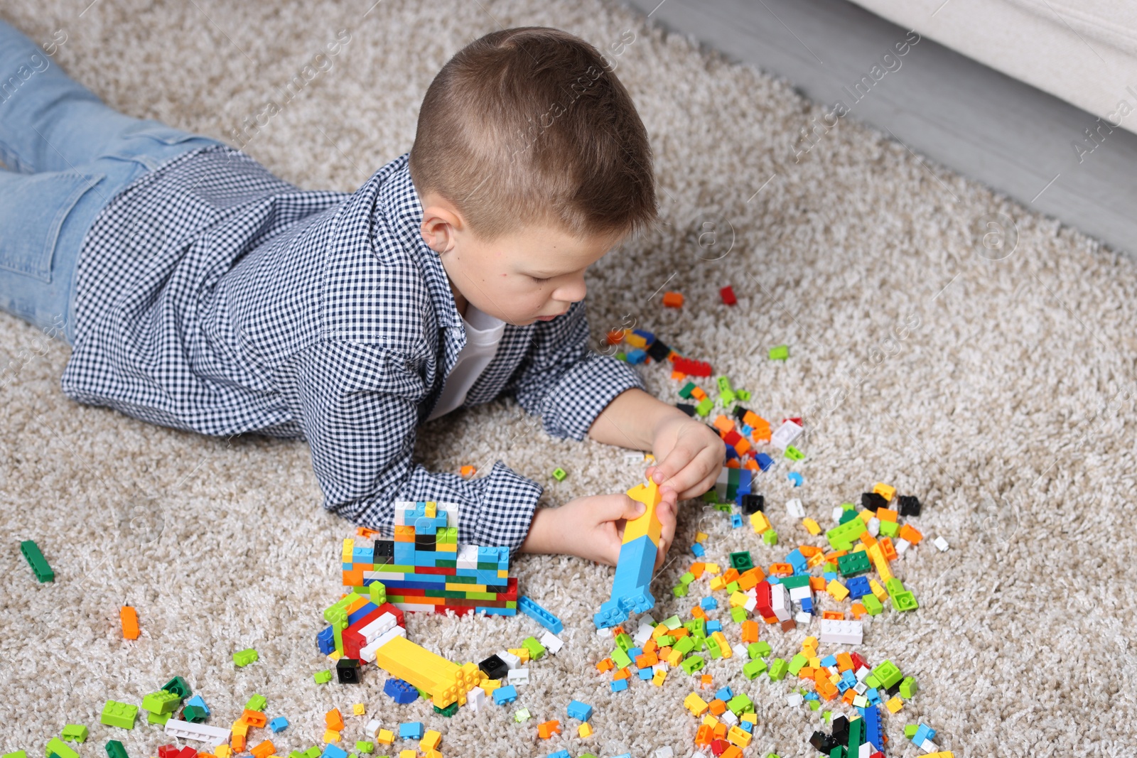 Photo of Cute boy playing with building blocks on floor at home