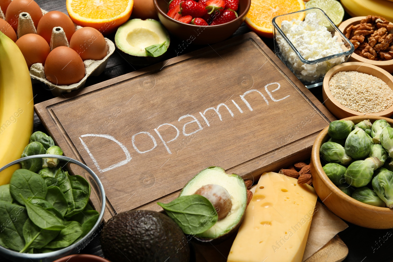 Photo of Wooden board with word Dopamine and different products as background, closeup