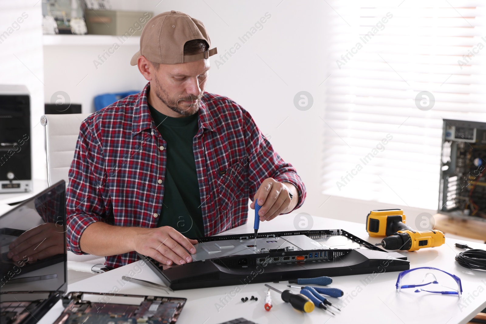 Photo of Man fixing computer monitor at white table