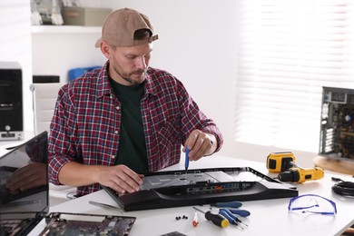 Photo of Man fixing computer monitor at white table