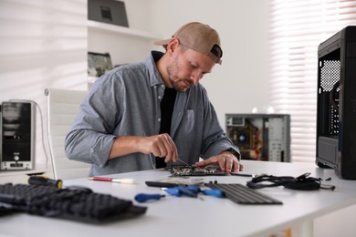 Photo of Man installing computer chip onto motherboard at white table