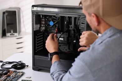 Photo of Man installing fan into computer at white table, closeup