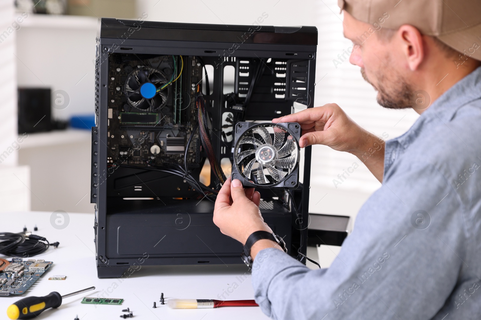 Photo of Man installing fan into computer at white table