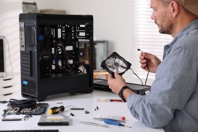 Photo of Man installing fan into computer at white table