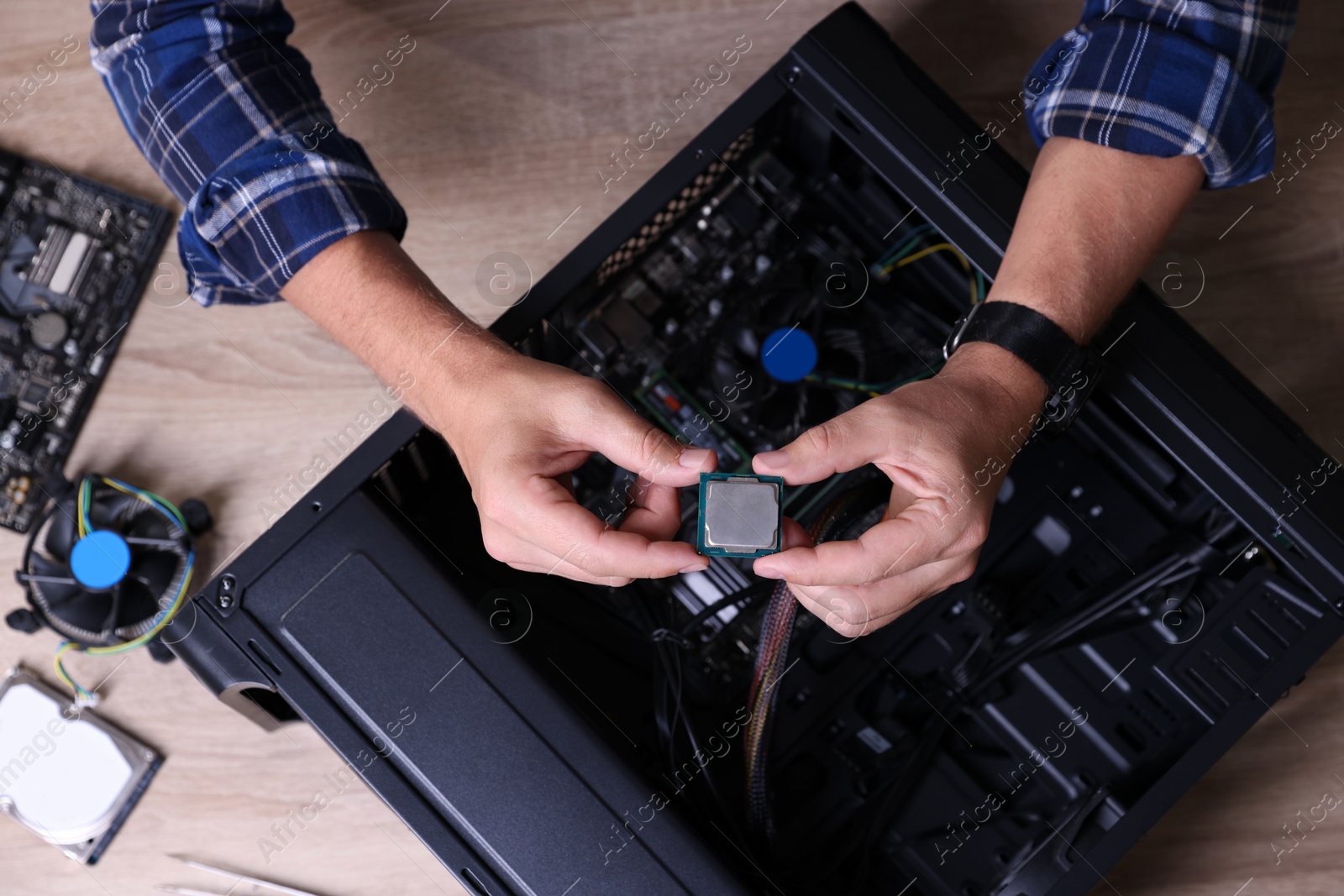 Photo of Man assembling new computer at wooden table, top view