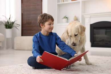 Photo of Boy reading book with his cute dog at home