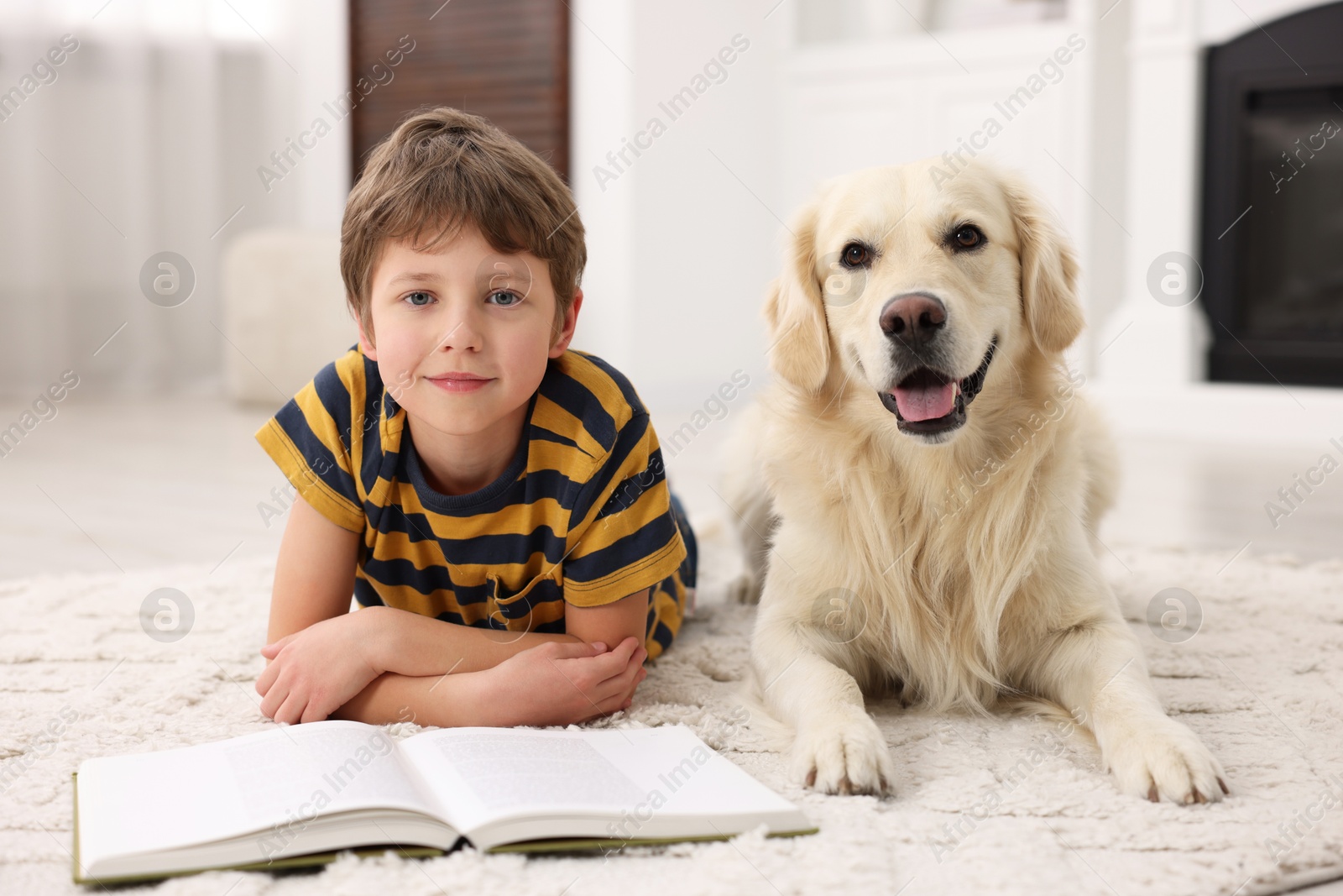 Photo of Boy reading book with his cute dog at home