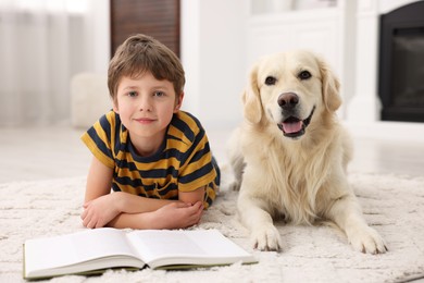 Photo of Boy reading book with his cute dog at home