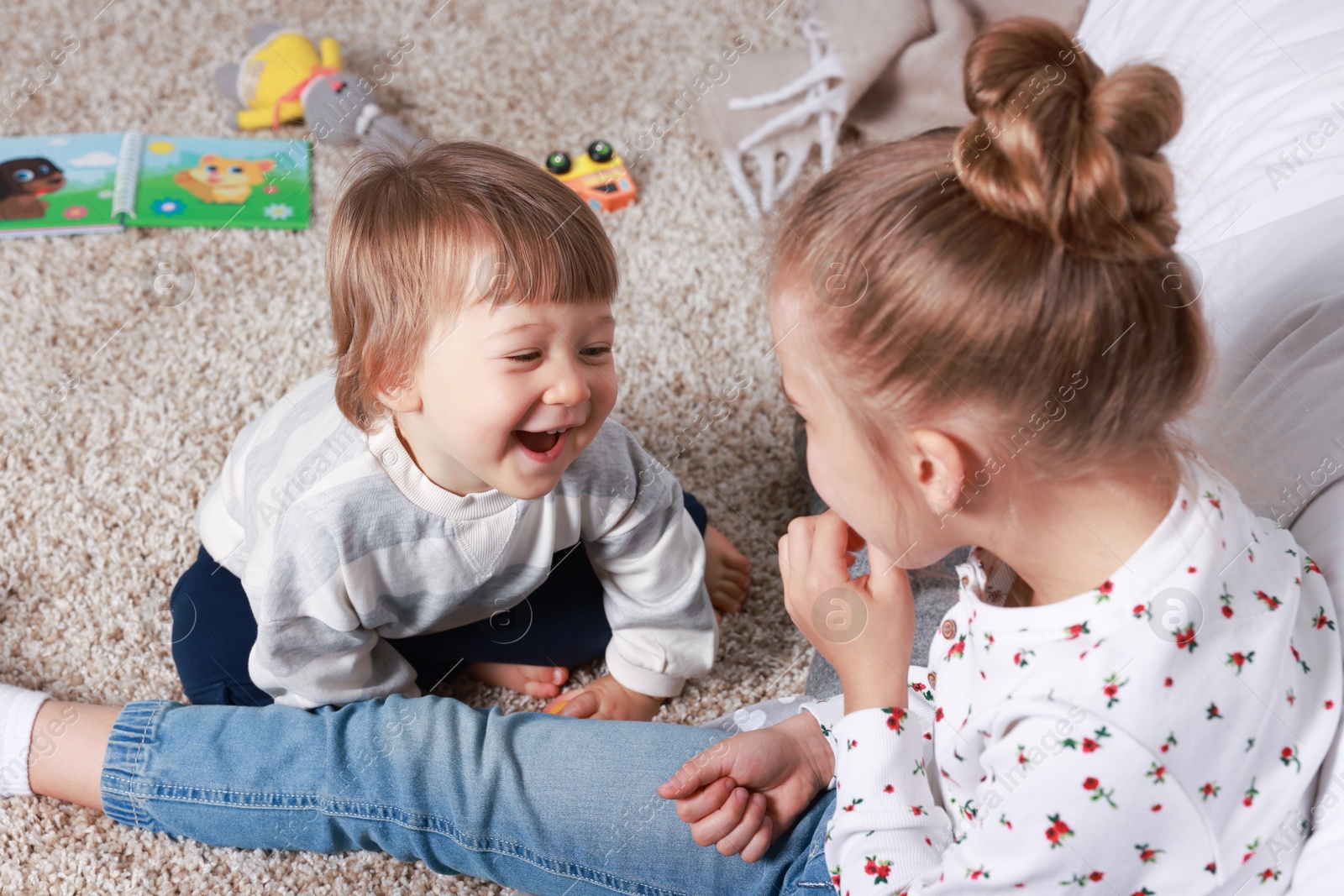 Photo of Sister and brother spending time together on floor at home