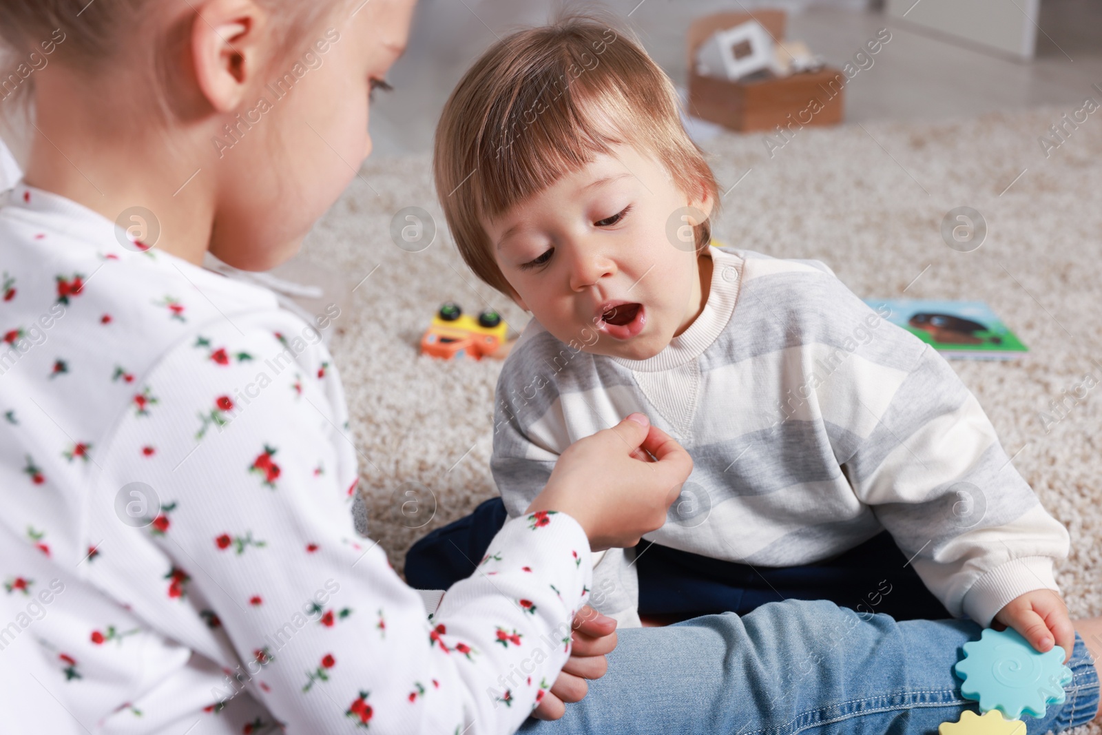 Photo of Sister and brother spending time together on floor at home