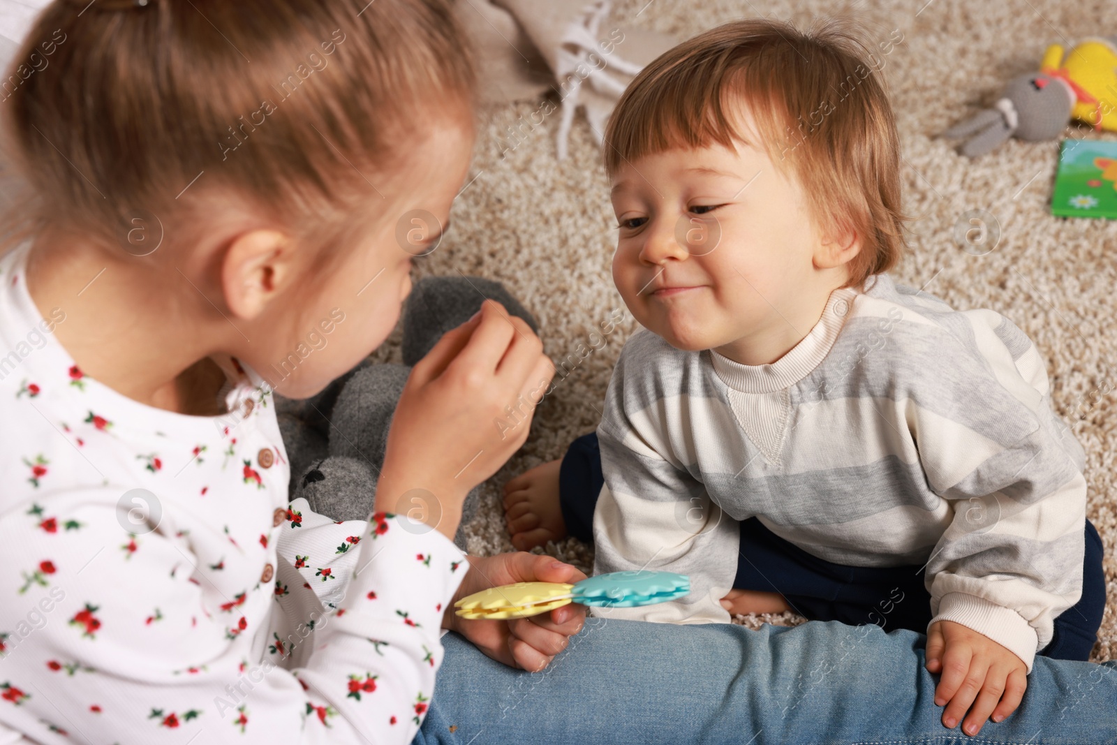 Photo of Sister and brother spending time together on floor at home