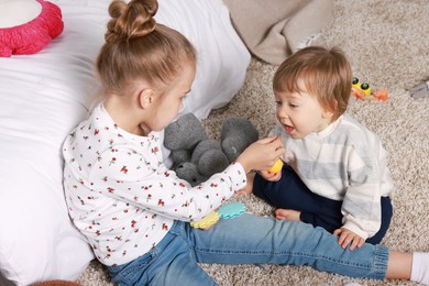 Photo of Sister and brother spending time together on floor at home